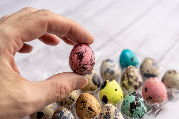 La mano tiene un bellissimo uovo di Pasqua colorate uova di Pasqua in un contenitore