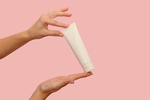 La mano tiene un contenitore bianco con crema cosmetica per la cura del corpo