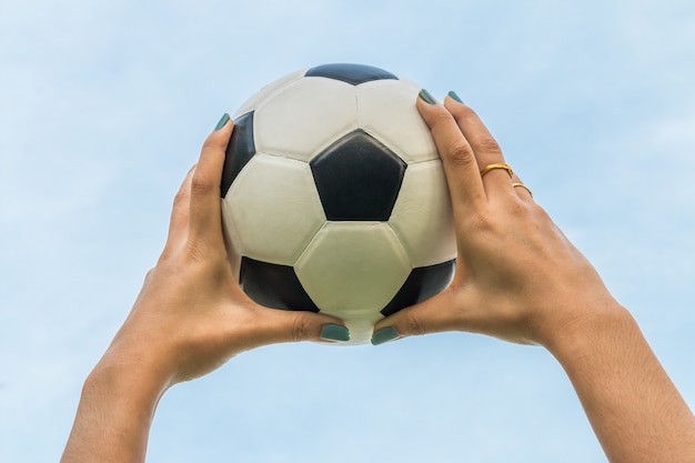 la mano tiene un pallone da calcio / footballin il cielo sul fondo del cielo blu