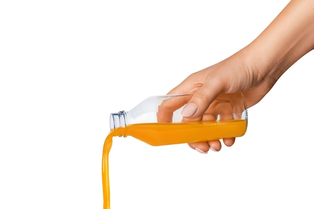 La mano tiene una bottiglia di succo d'arancia Succo sta versando da una bottiglia Isolato su sfondo bianco