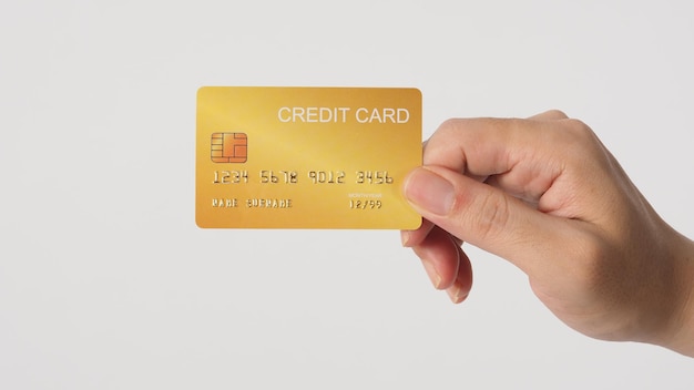 La mano tiene una carta di credito d'oro isolata su uno sfondo bianco