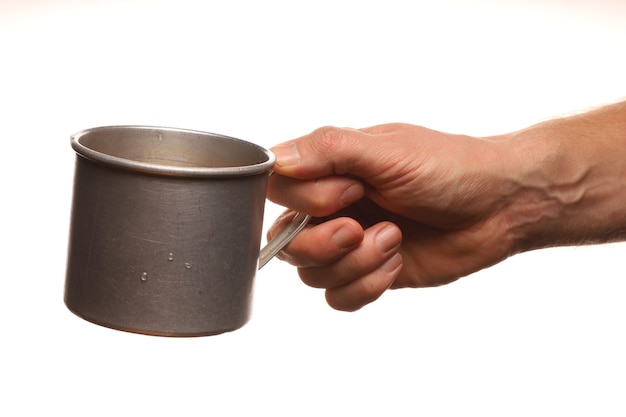 La mano tiene una vecchia tazza di metallo