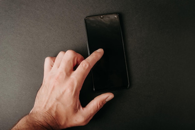 La mano tocca lo schermo del telefono su sfondo nero