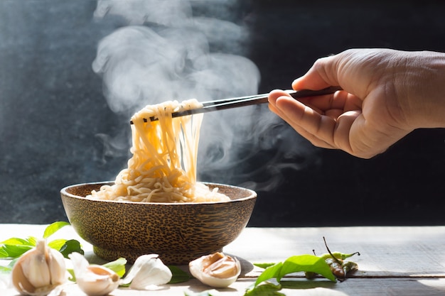 La mano usa le bacchette per raccogliere gustosi spaghetti