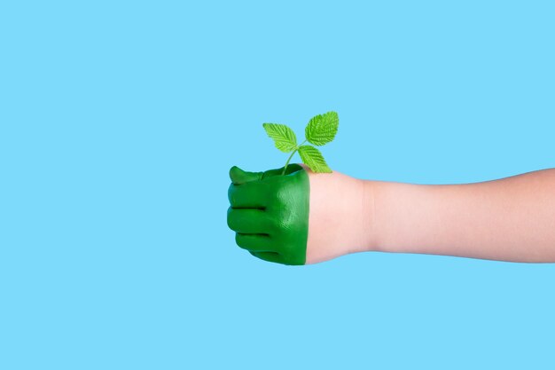 La mano verde dei bambini che tiene una pianta piegata