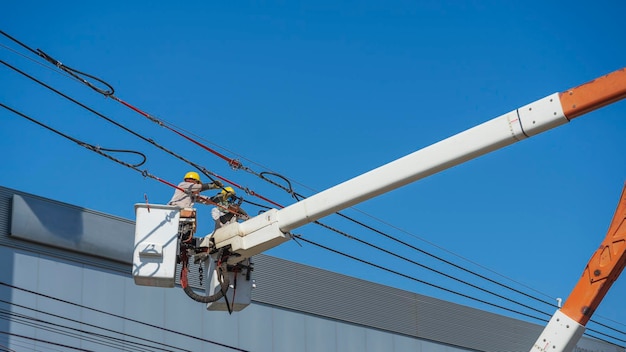 La manutenzione degli elettricisti lavora con l'elettricità ad alta tensione sulla benna idraulica