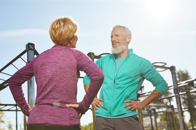 La mattina esercita una coppia di famiglia anziana felice in abiti sportivi che fanno ginnastica insieme in palestra all'aperto