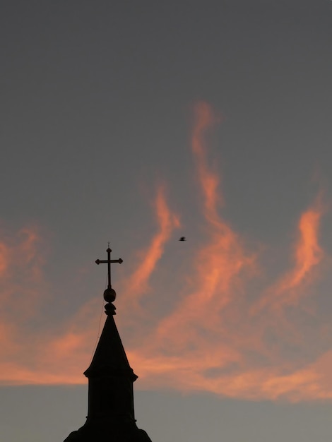 La mattina illumina il cielo come la sagoma di fuoco della cima della chiesa e un uccello in volo