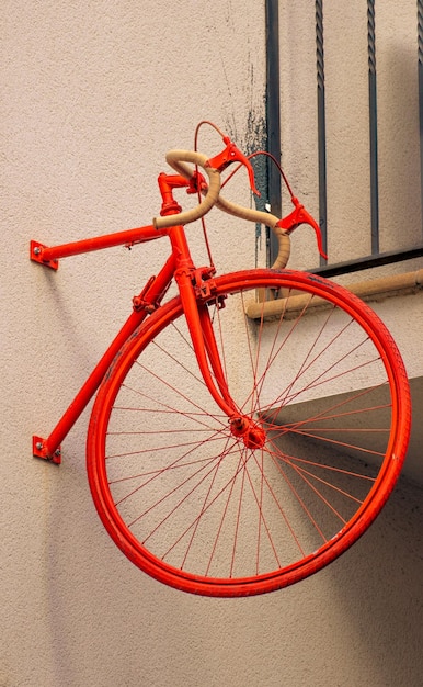 La metà anteriore di una bicicletta rossa vintage appuntata al muro di un edificio minimalista