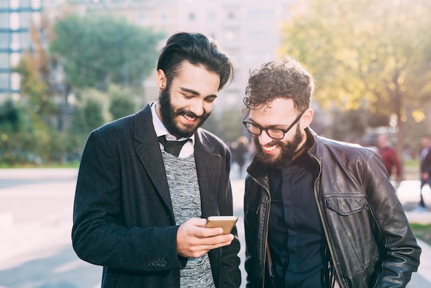 La metà di lunghezza di due giovani uomo d&#39;affari moderno barbuto facendo uso dello Smart Phone