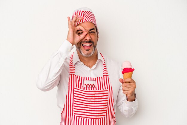 La mezza età caucasica ice maker uomo caucasico tenendo un gelato isolato su sfondo bianco eccitato mantenendo il gesto ok sull'occhio.