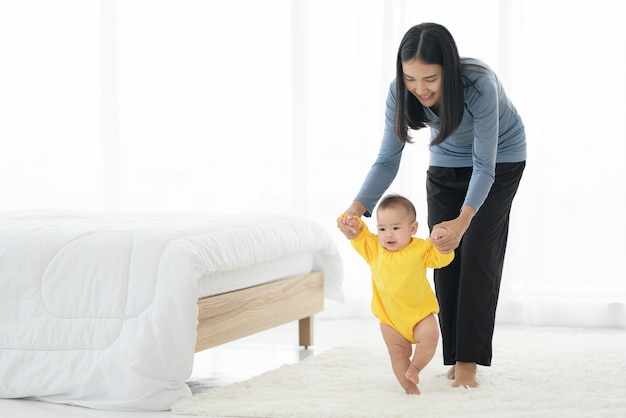 La mia bambina muove i primi passi. famiglia felice piccolo bambino che impara a camminare con la madre aiuta a casa