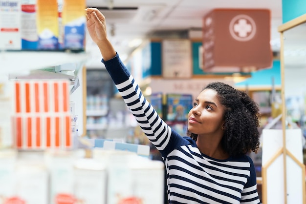 La mia farmacia locale è sempre completamente rifornita di prodotti convenienti Inquadratura di una giovane donna che guarda i prodotti in una farmacia