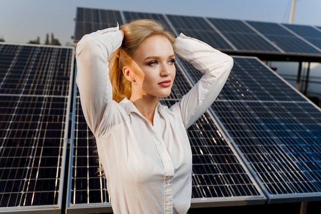 La modella bionda con i pannelli solari sta in fila per terra