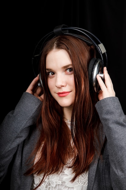 La modella dai capelli scuri è in posa in uno studio buio con le cuffie in testa