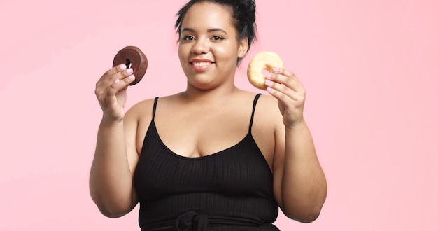 La modella plus size in studio spara sorridendo e mangia una ciambella