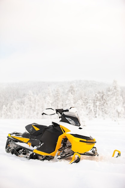 La motoslitta gialla è in piedi su un campo innevato sullo sfondo di un paesaggio panoramico invernale