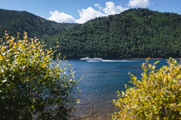 la nave da crociera sta navigando sull'acqua cristallina blu sullo sfondo di colline boscose verdi