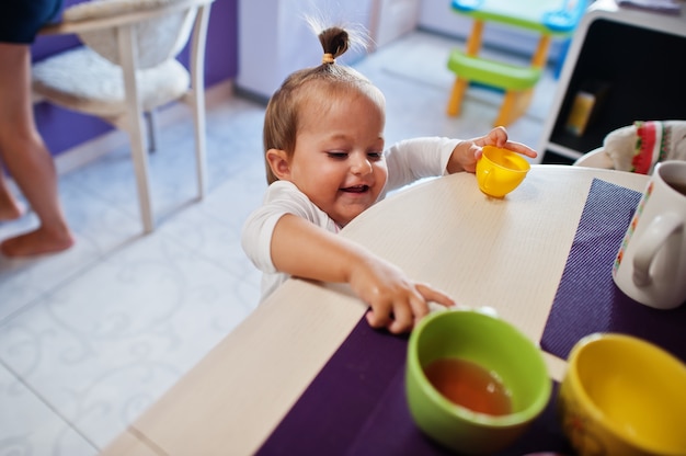 La neonata beve il succo di composta in cucina, i momenti felici dei bambini.