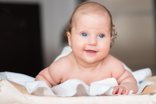 La neonata felice si trova su un lenzuolo bianco nella sua stanza