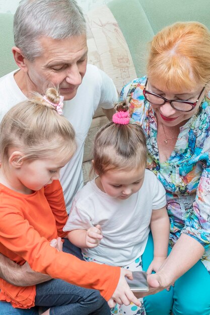 la nipote usa lo smartphone mentre è seduta sul nonno