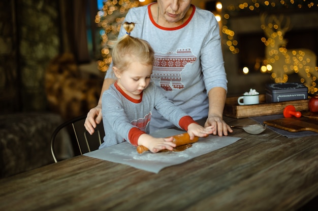 La nonna aiuta sua nipote a stendere la pasta per un tradizionale biscotto allo zenzero di Natale