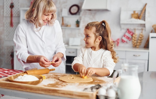 La nonna anziana con la sua nipotina cucina dolci per Natale in cucina