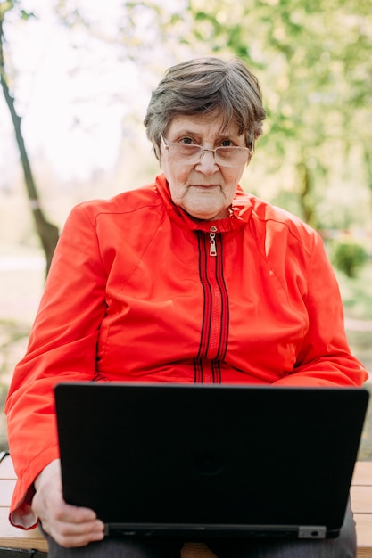 La nonna anziana felice usa la comunicazione del computer portatile all'esterno