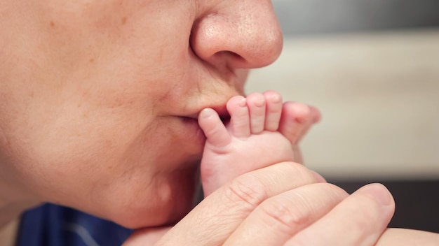 La nonna bacia i piccoli piedi nudi con le piccole dita del bambino