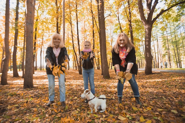 La nonna e la madre con la nipote vomitano foglie d'autunno nel parco autunnale e si divertono. Generazione, tempo libero e concetto di famiglia