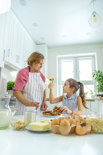 La nonna e la nipote cuociono i biscotti in cucina Messa a fuoco selettiva