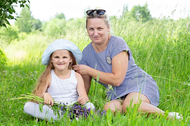 La nonna e la nipote felici sono sedute sull'erba nel parco