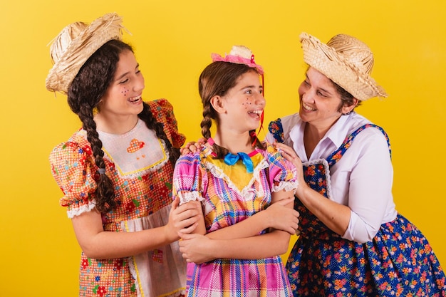 La nonna e le sue due nipoti vestite con i tipici abiti della Festa Junina si abbracciano e sorridono