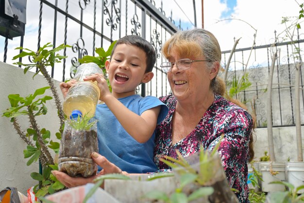 La nonna insegna a suo nipote a riciclare piantando in bottiglie di plastica