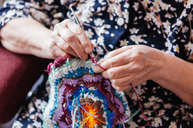 La nonna lavora all'uncinetto le cose. Le mani si chiudono