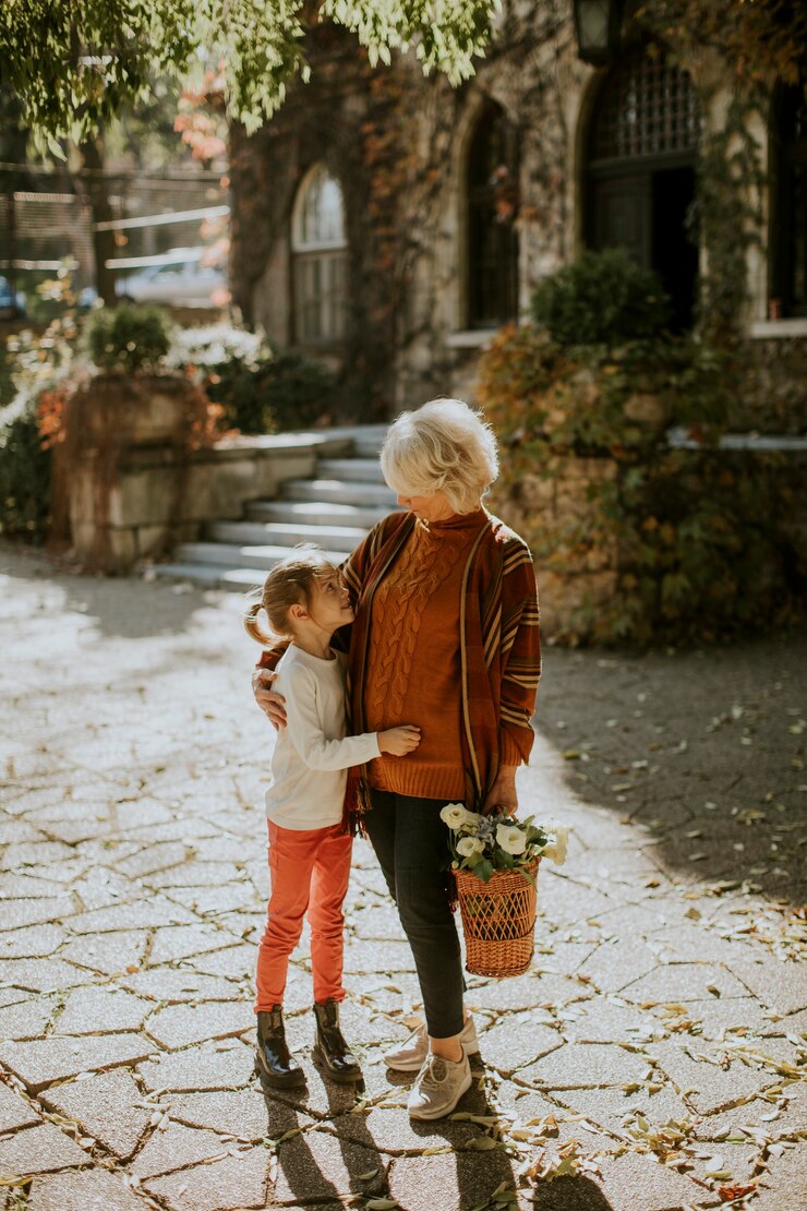 Foto la nonna si diverte con la sua graziosa nipotina e tiene in mano un cesto pieno di fiori