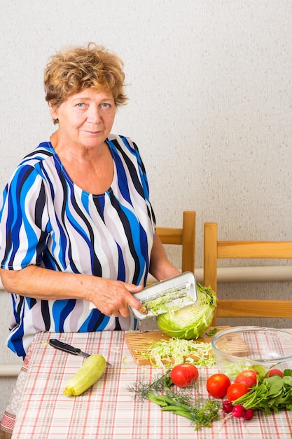 La nonna taglia il cavolo sul tavolo della cucina