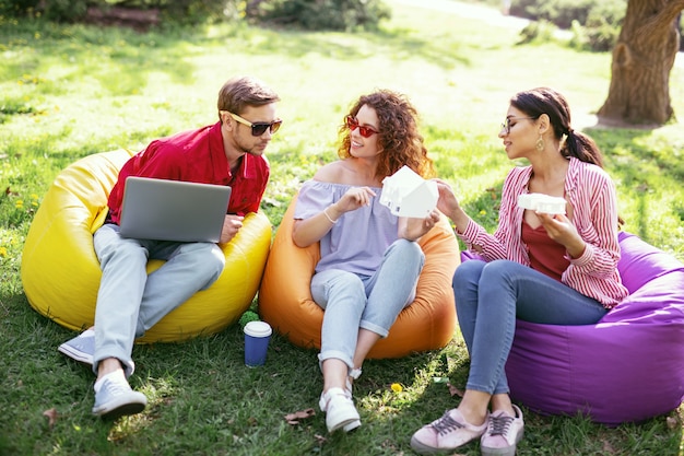 La nostra startup. Sorridenti colleghi ambiziosi seduti all'aria aperta e che lavorano al progetto