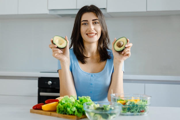 La nutrizionista femminile mostra le verdure fresche dell'avocado e un metro a nastro sul suo tavolo