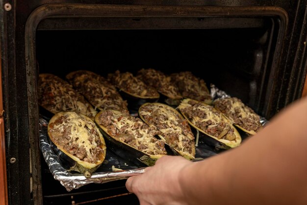 La padrona di casa mette in forno una teglia con melanzane ripiene di carne