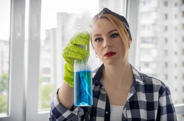 La padrona di casa spruzza un detergente per vetri sulla finestra Il concetto di pulizia in casa