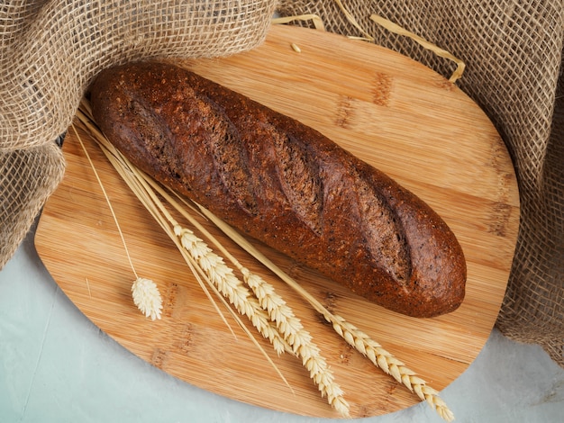 La pagnotta di pane con le orecchie si trova su una tavola di legno