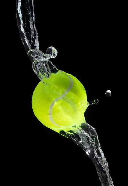 La palla da tennis colpisce l'acqua e schizza in aria Verda La pallina da tennis vola nella pioggia e schizza Spin schizza nelle gocce d'acqua Sfondio nero azione di congelamento isolata