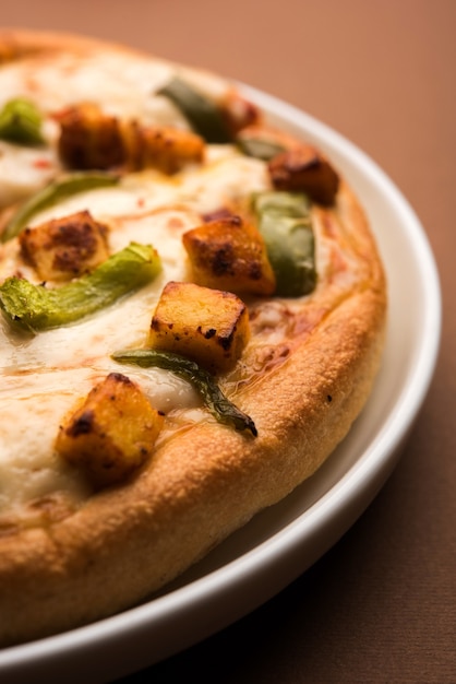 La Paneer Pizza è una versione indiana del piatto italiano condita con ricotta, servita in un piatto con salsa bianca. messa a fuoco selettiva