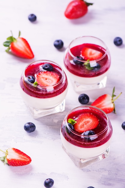 La panna cotta del dessert con la fragola, il mirtillo e la bacca freschi sauce su backgroundce di legno