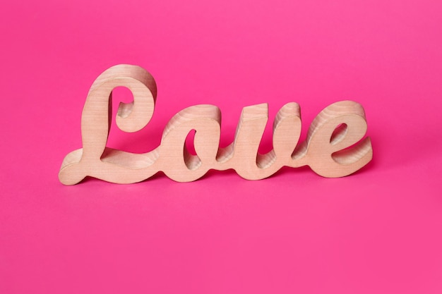 la parola amore in lettere di legno su sfondo rosa