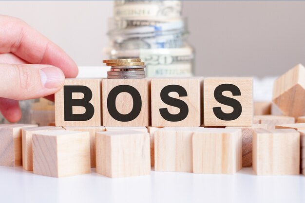 La parola Boss sui blocchi di legno e una banca con soldi in tavola, concetto di affari