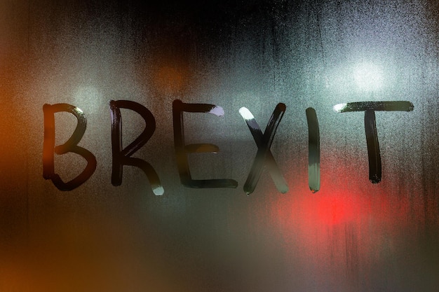 La parola brexit scritta sul primo piano di vetro della finestra bagnata di notte con sfondo sfocato