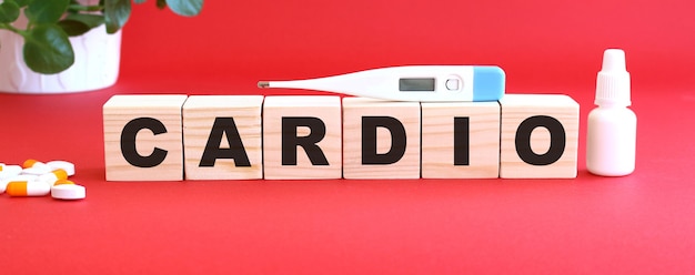 La parola CARDIO è composta da cubi di legno su una superficie rossa con farmaci.