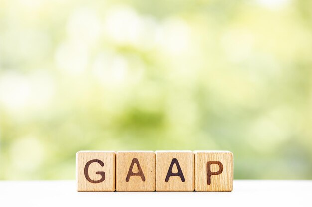 La parola GAAP è scritta su cubi di legno su uno sfondo verde estivo Primo piano di elementi in legno